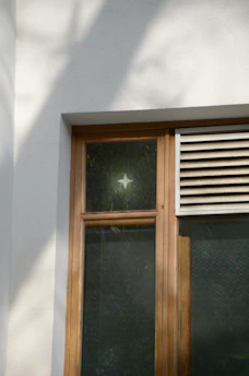 Hands installing an air vent on a wooden window frame in a cozy home setting.
