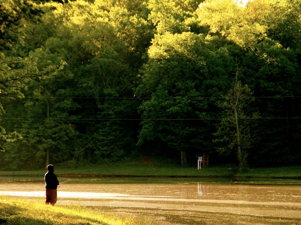 a person standing on a dirt road near a forest