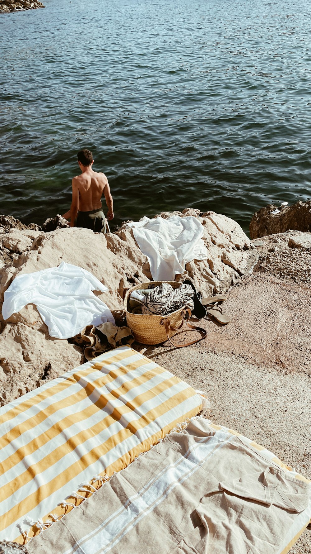 a man sitting on a beach next to a body of water