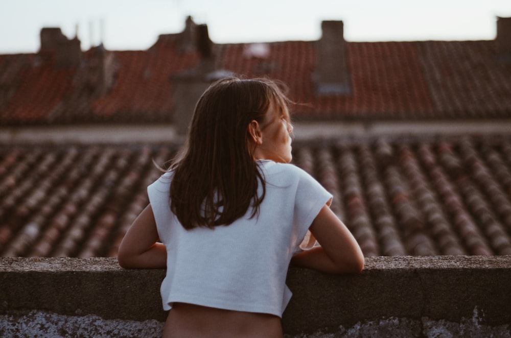 a little girl looking out over a rooftop