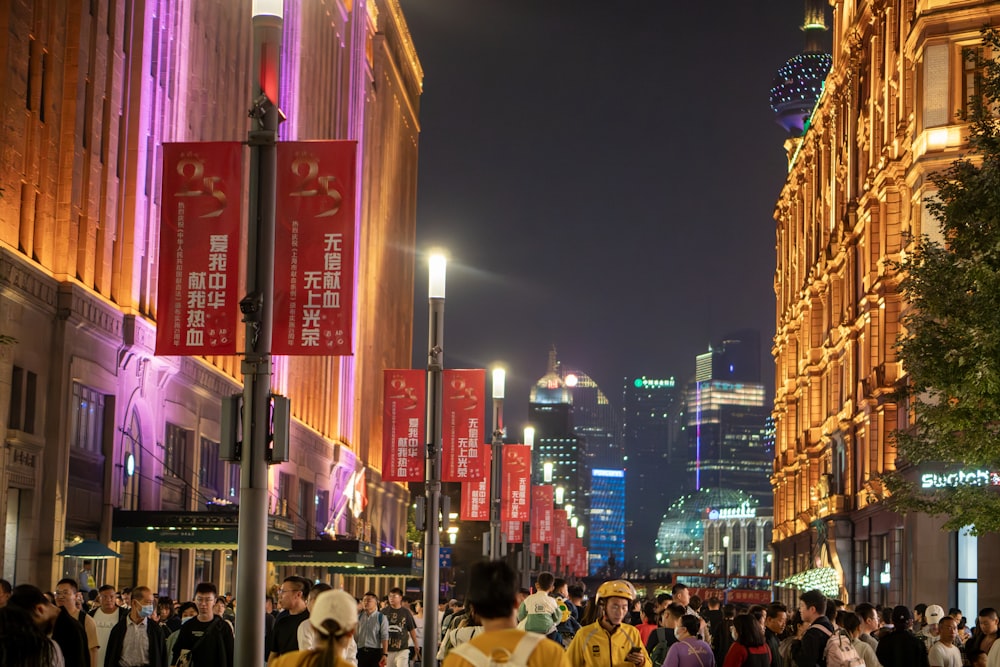 a crowd of people walking down a street next to tall buildings