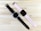 Two wristwatches are placed on a light wooden surface. The watch on the left has a black round face with a black strap, featuring several vent-like cutouts. The watch on the right has a rectangular black face with a light pink strap, also featuring cutouts along its length.