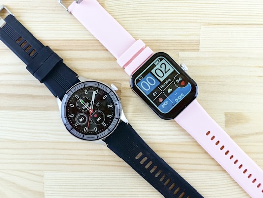 a smart watch sitting next to a smart watch on a wooden table