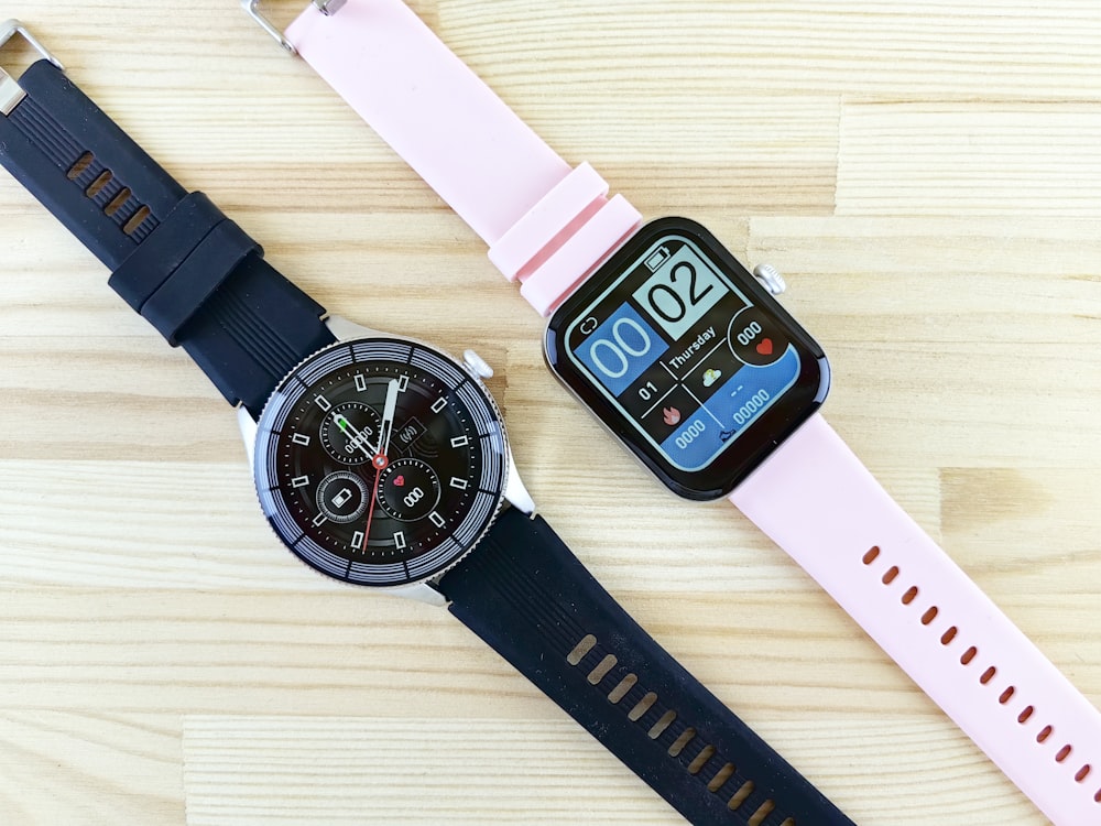 a smart watch sitting next to a smart watch on a wooden table