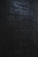 Close-up of an ancient, cryptic symbol glowing violet on a dark stone.