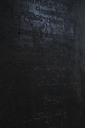 Close-up of an ancient, cryptic symbol glowing violet on a dark stone.