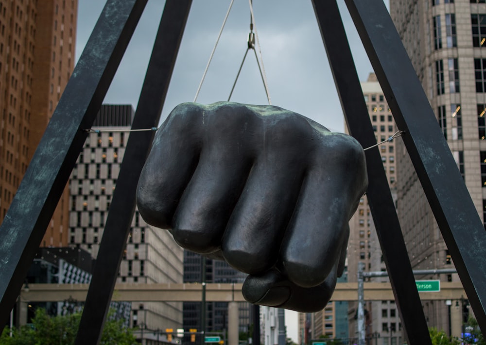 a statue of a fist is suspended by a crane