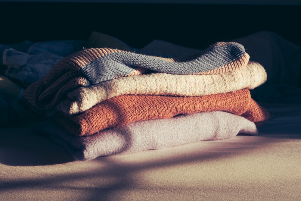 a pile of folded towels sitting on top of a bed