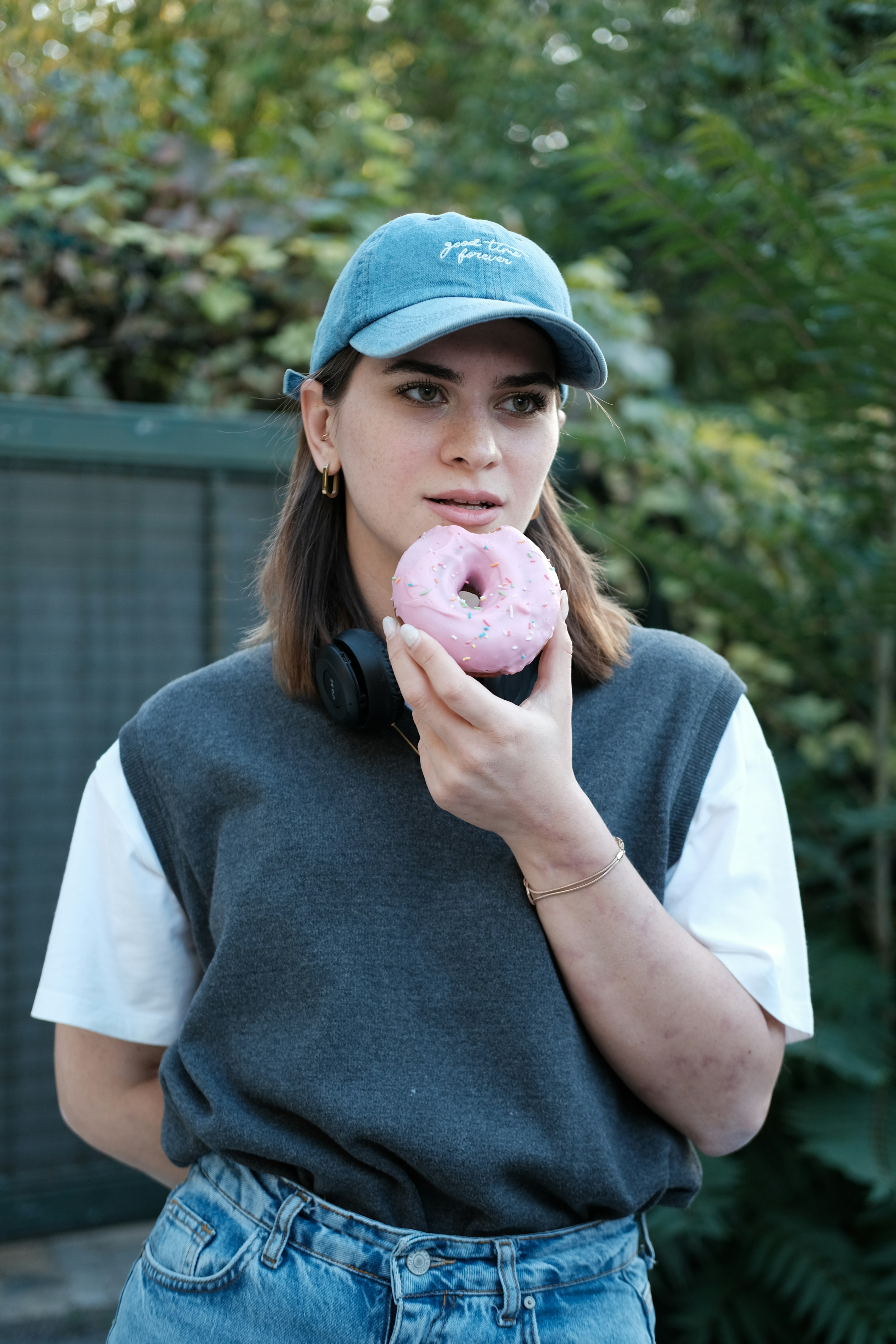 a woman holding a pink doughnut in her hand