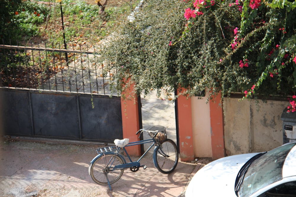 a bicycle parked next to a fence and a car