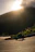 A rider on a motorcycle crossing a scenic mountain trail at sunrise.