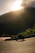 A rider on a motorcycle crossing a scenic mountain trail at sunrise.