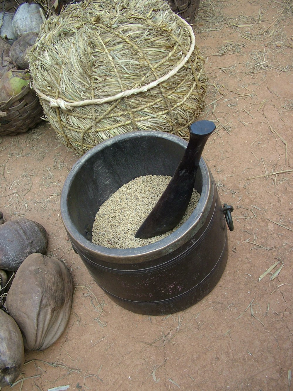 a large black bowl filled with food next to a pile of hay