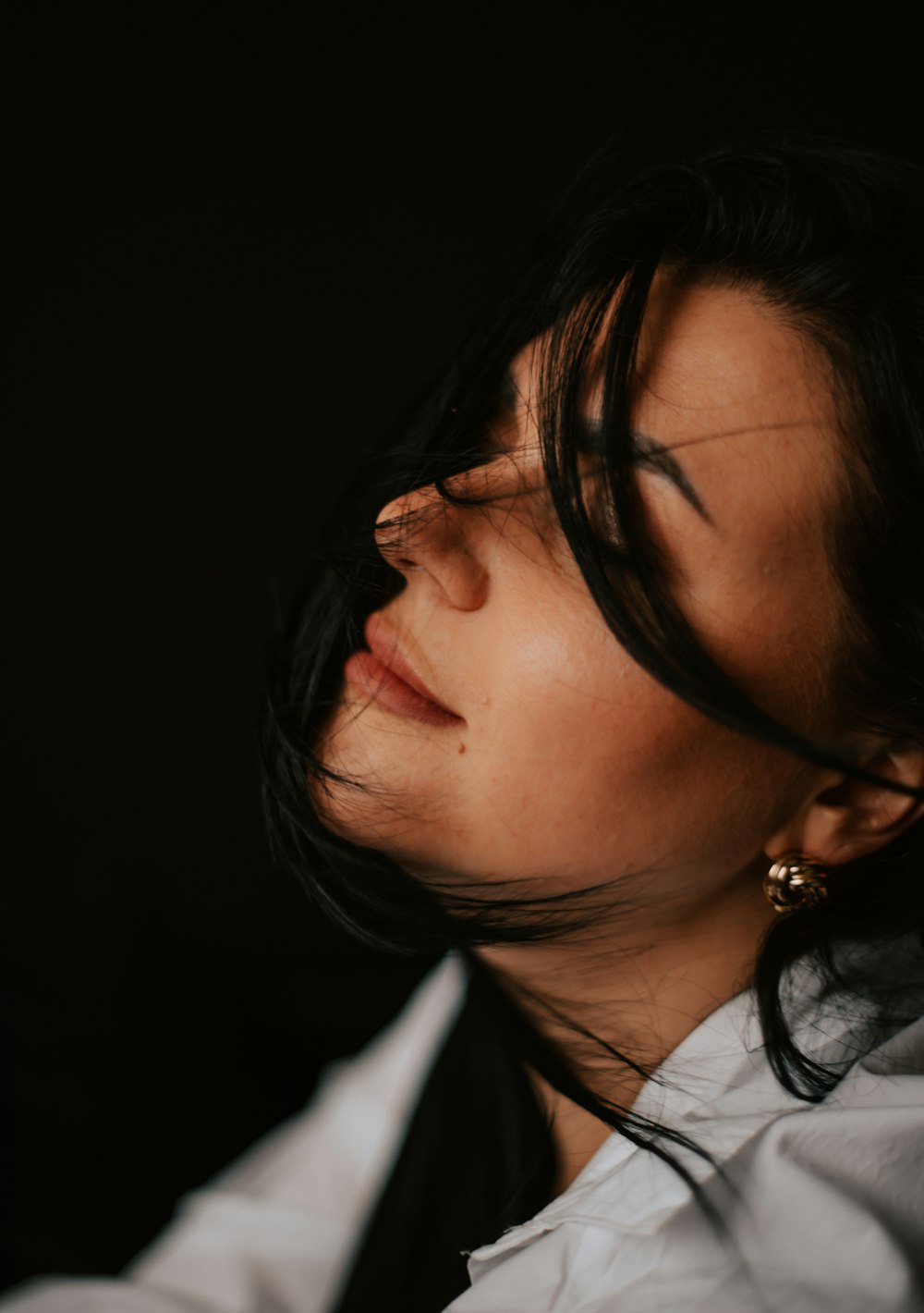 a woman in a white shirt and gold earrings