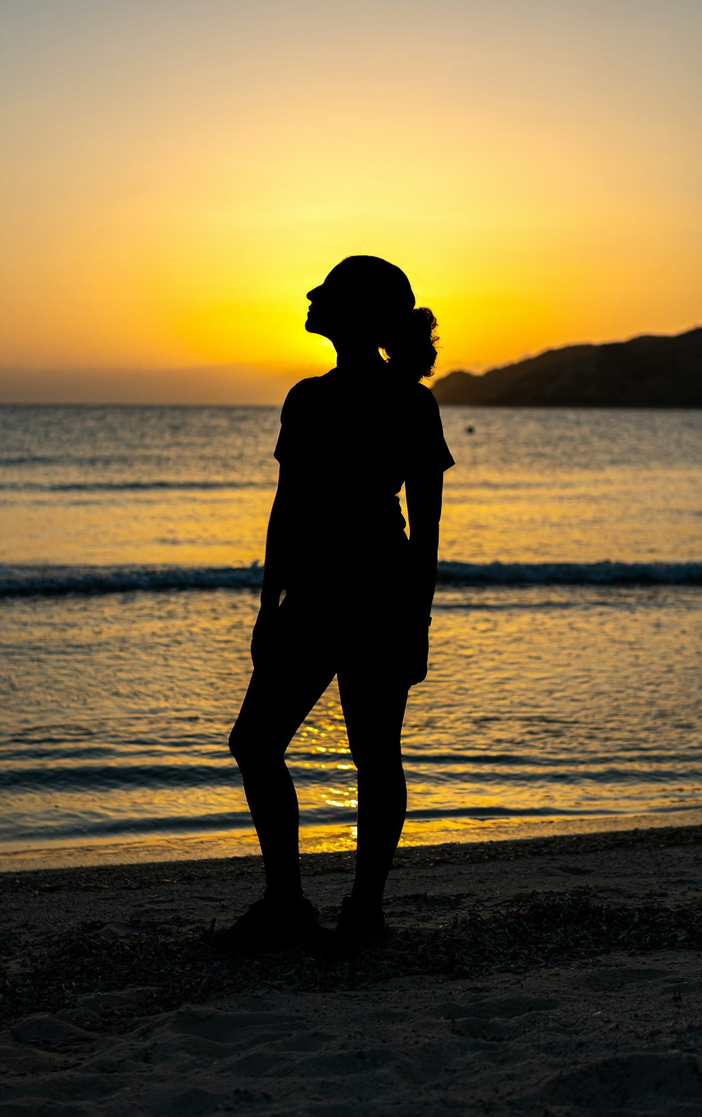 una persona de pie en una playa al atardecer