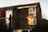 A wooden house with large windows reflecting the warm light of sunset. The exterior features horizontal wooden paneling, and there is a birdhouse mounted on a tree stump in the foreground. Surrounding the house are some trees and bushes, contributing to a natural setting.