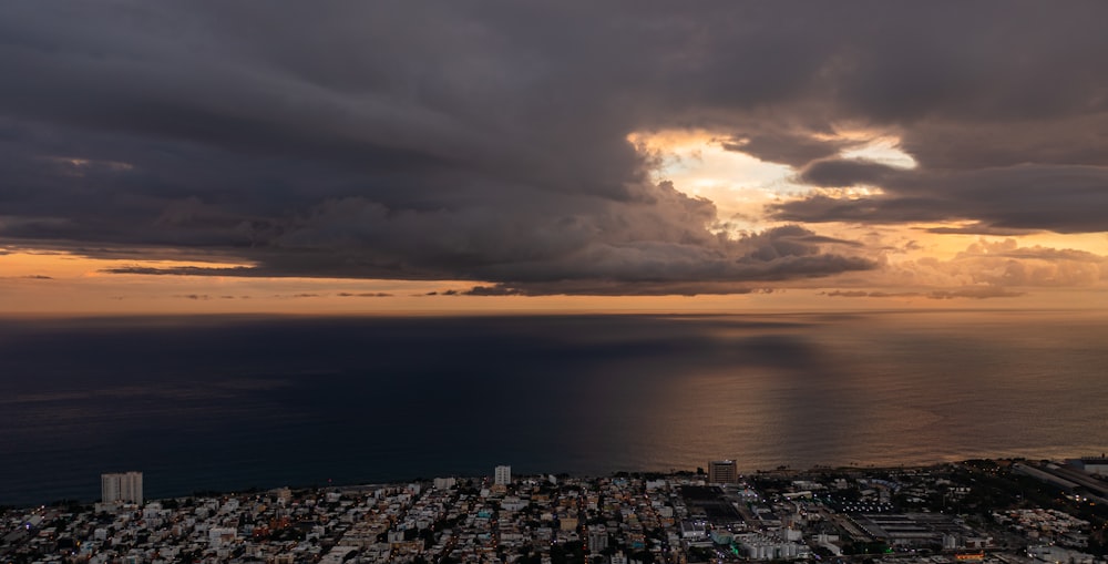 a view of a city and the ocean at sunset