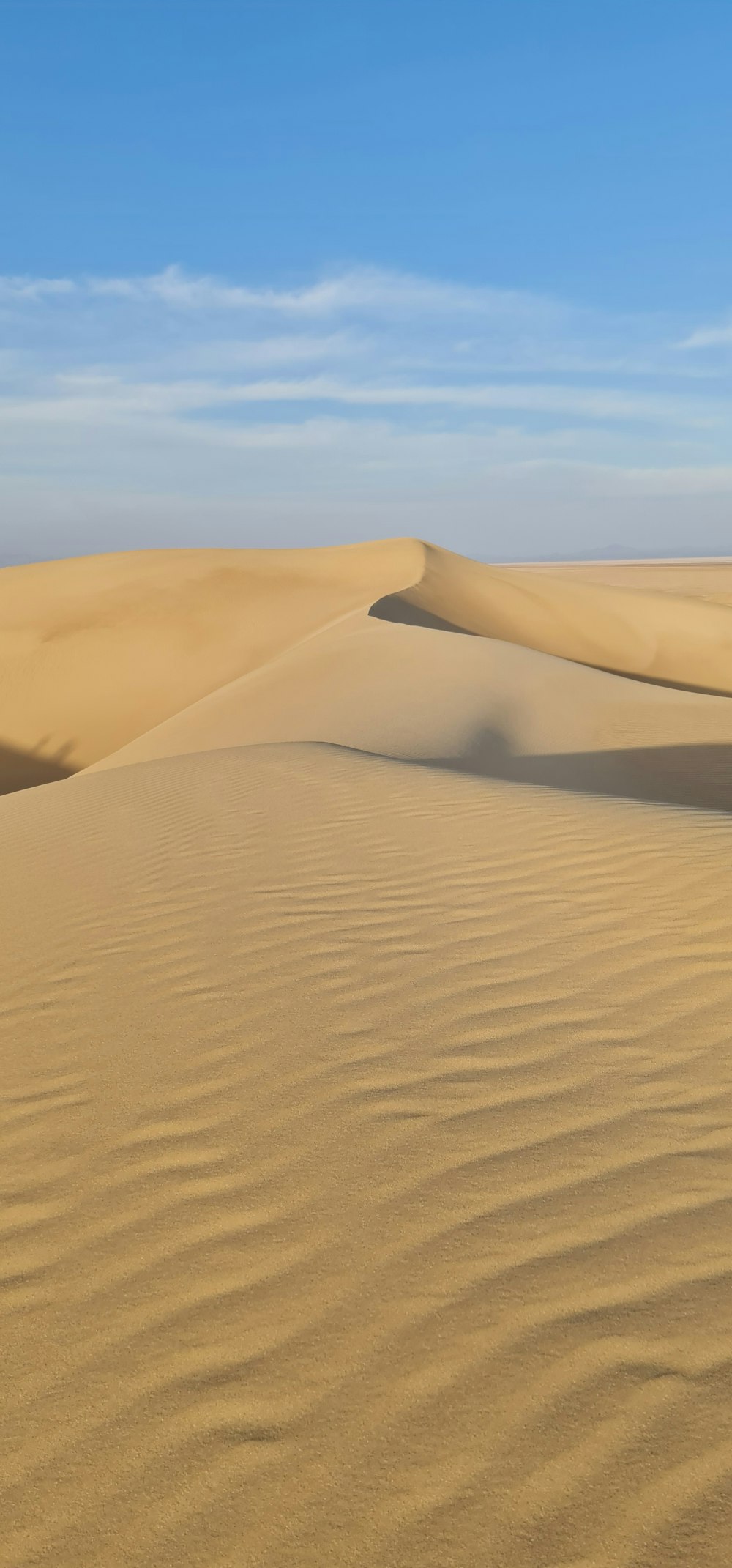 a desert landscape with sand dunes and a blue sky