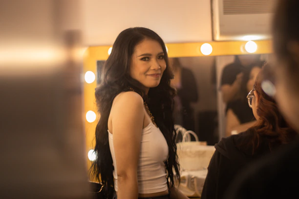 Close-up of plus-size woman smiling while trying on a stylish casual top in a cozy room