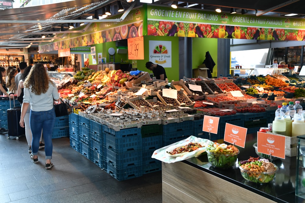 a woman walking through a market filled with lots of food