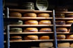 Cheese wheels stacked on shelves in a cozy cellar.
