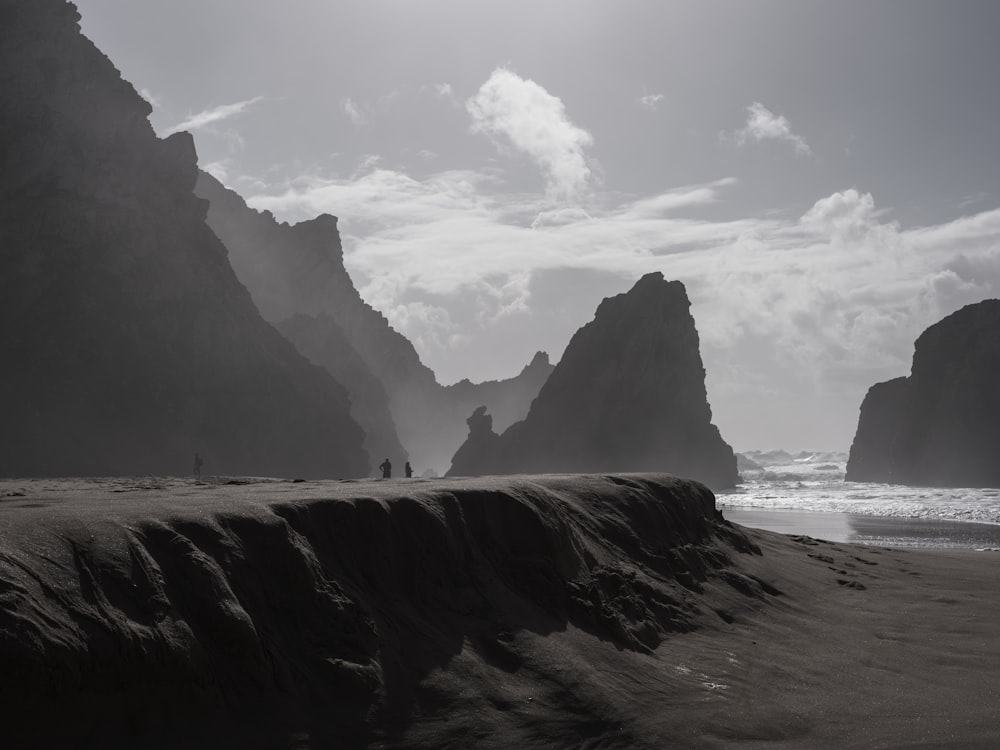 a black and white photo of people walking on the beach