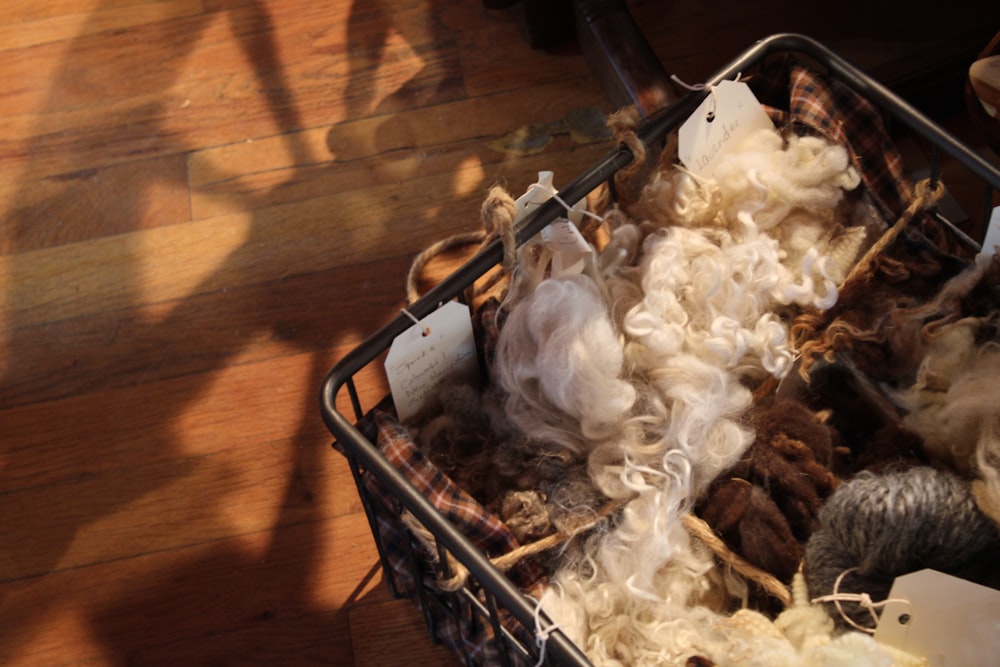 a basket filled with lots of wool on top of a wooden floor