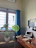 A cozy home office setup featuring a simple wooden desk with a laptop and a small plant.