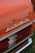 Close-up view of a vintage car's rear section with the word 'AUTOMATIC' prominently displayed in chrome lettering. The car features a shiny orange paint job and distinct tail lights with red and white sections. The bumper has a chrome finish.