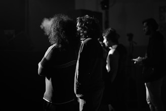 A vintage black-and-white photo of a clandestine meeting in a dimly lit room with shadowy figures.