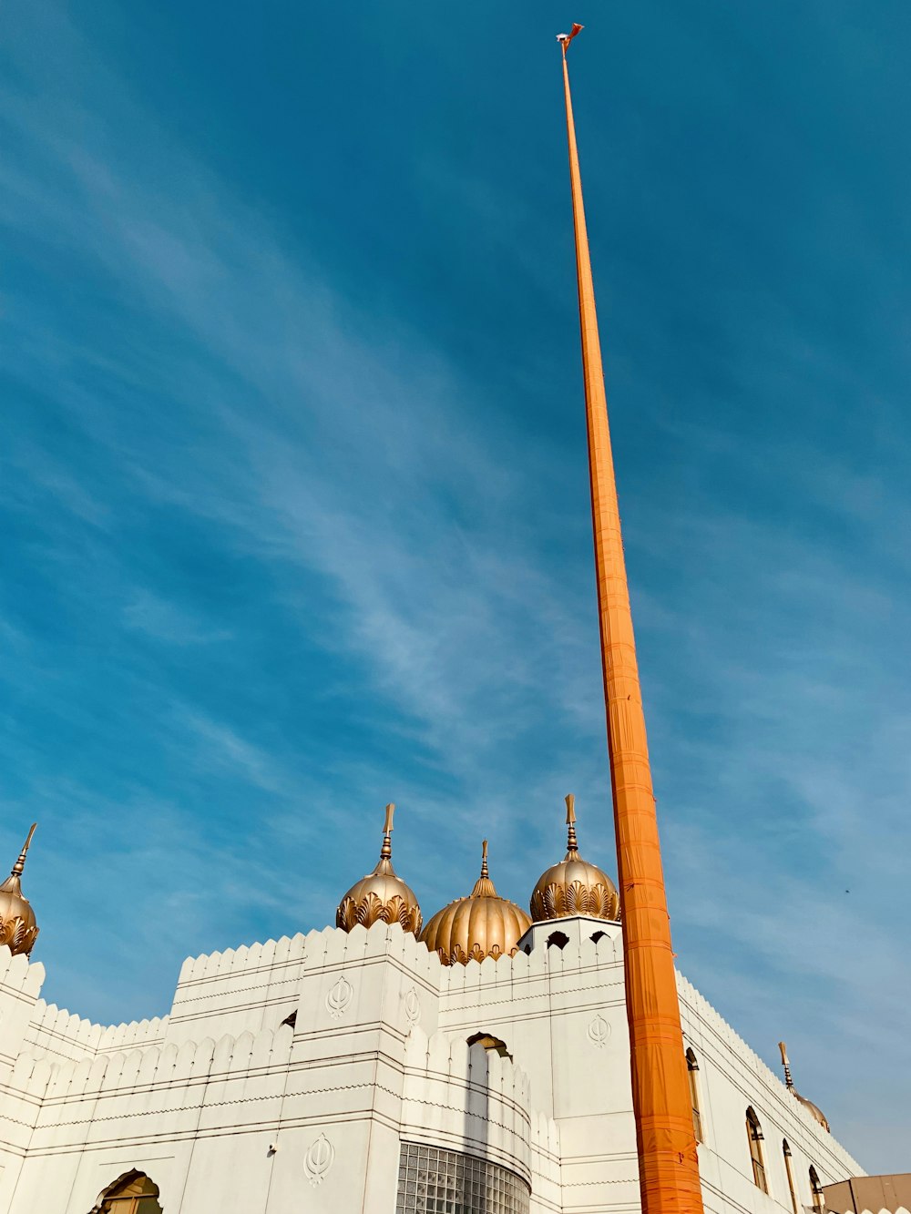 a tall orange object in front of a white building