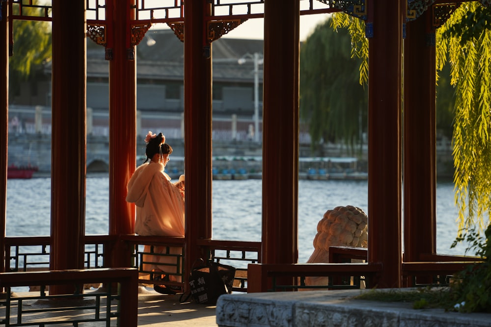 a woman sitting on a bench in front of a lake