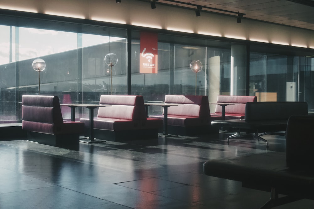 a waiting area with chairs and tables in front of large windows