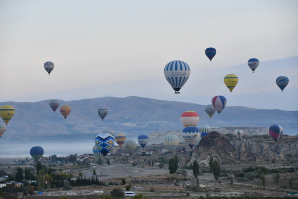 Colorful hot air balloons floating over lush green hills during a scenic adventure tour.