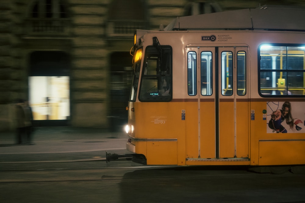 a yellow trolley driving down a street next to a tall building