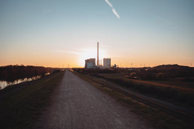 A sleek electrical power plant at sunset with glowing transmission lines stretching across the horizon.