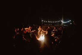a group of people sitting around a campfire at night