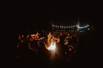 a group of people sitting around a campfire at night