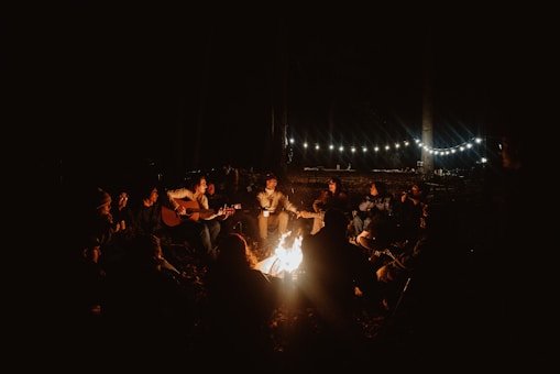 a group of people sitting around a campfire at night