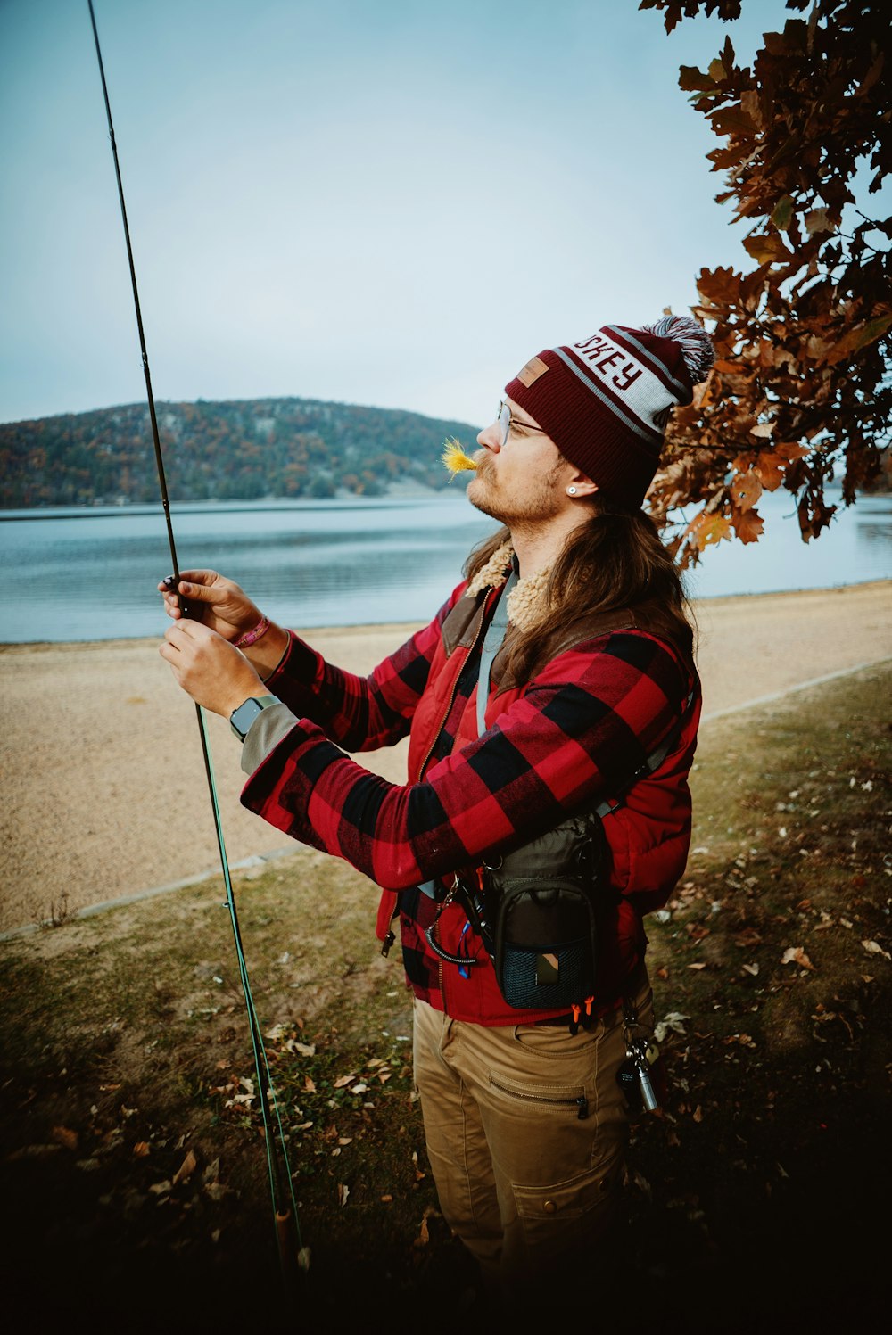 a man holding a fishing pole while standing next to a tree