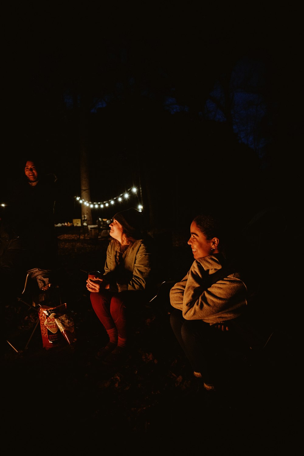 zwei Menschen, die nachts um ein Lagerfeuer sitzen