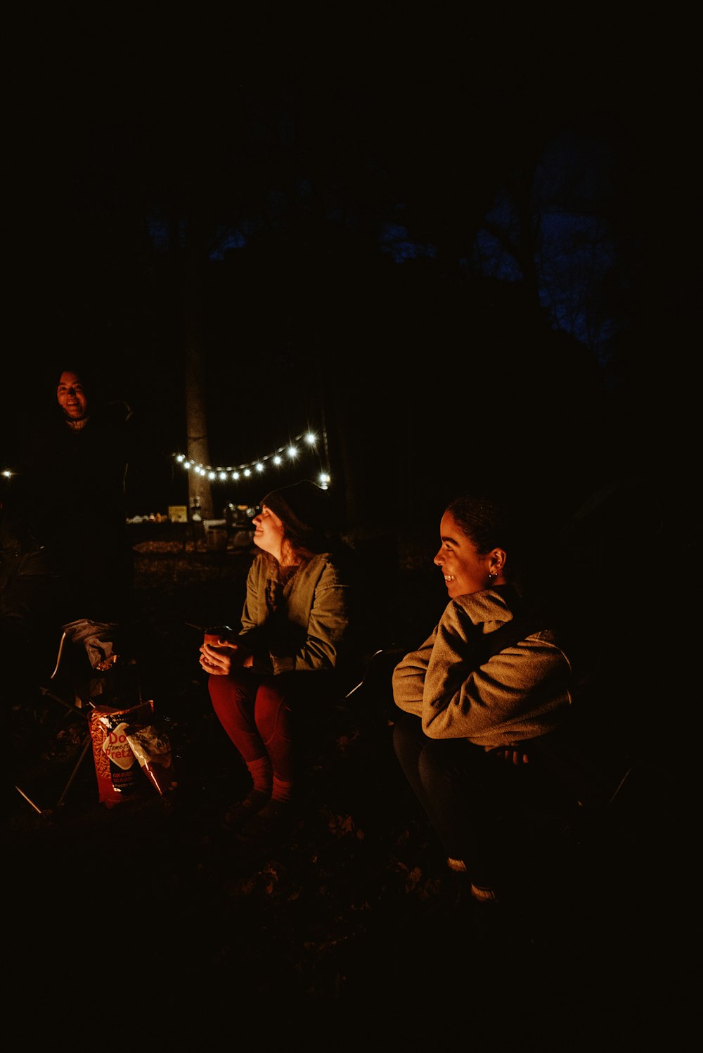 two people sitting around a campfire at night