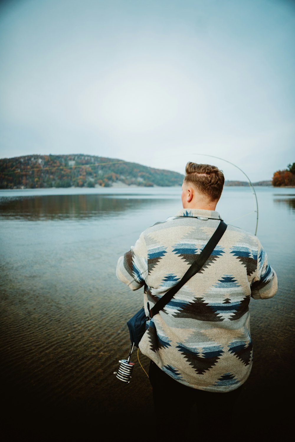 un homme debout sur une plage tenant une canne à pêche