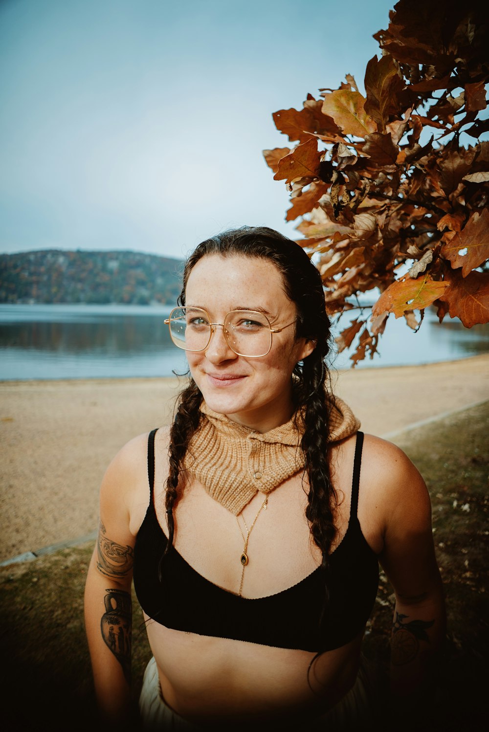 a woman wearing glasses standing next to a tree