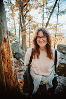 A smiling person journaling outdoors, sunlight filtering through trees.