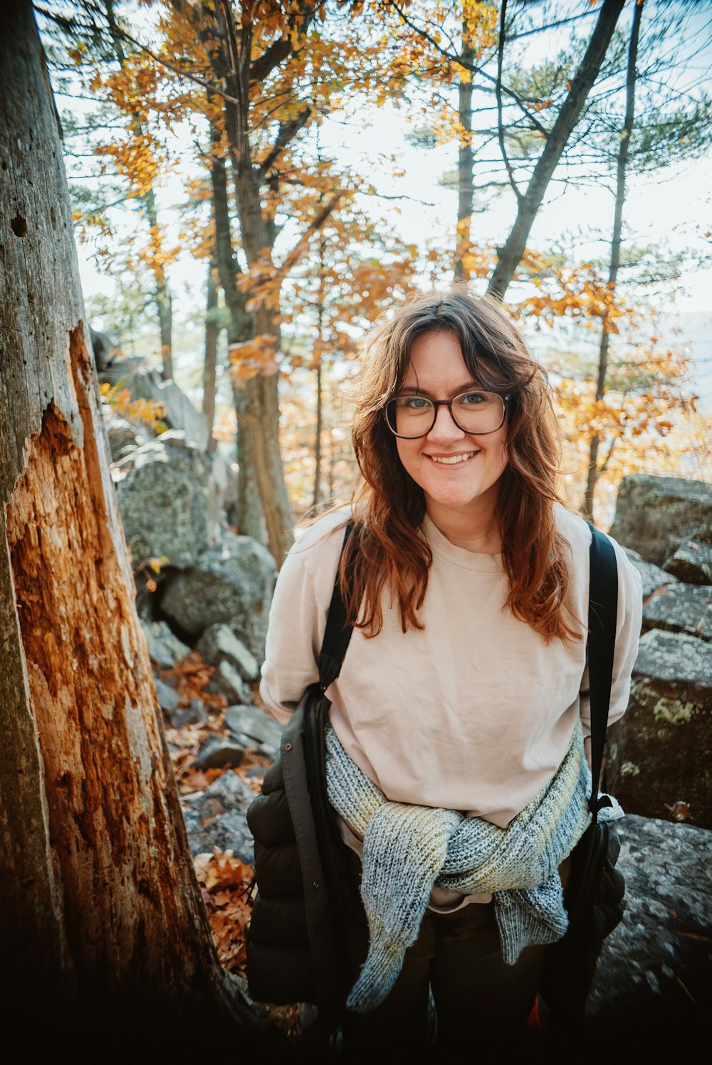 a woman with glasses standing in the woods
