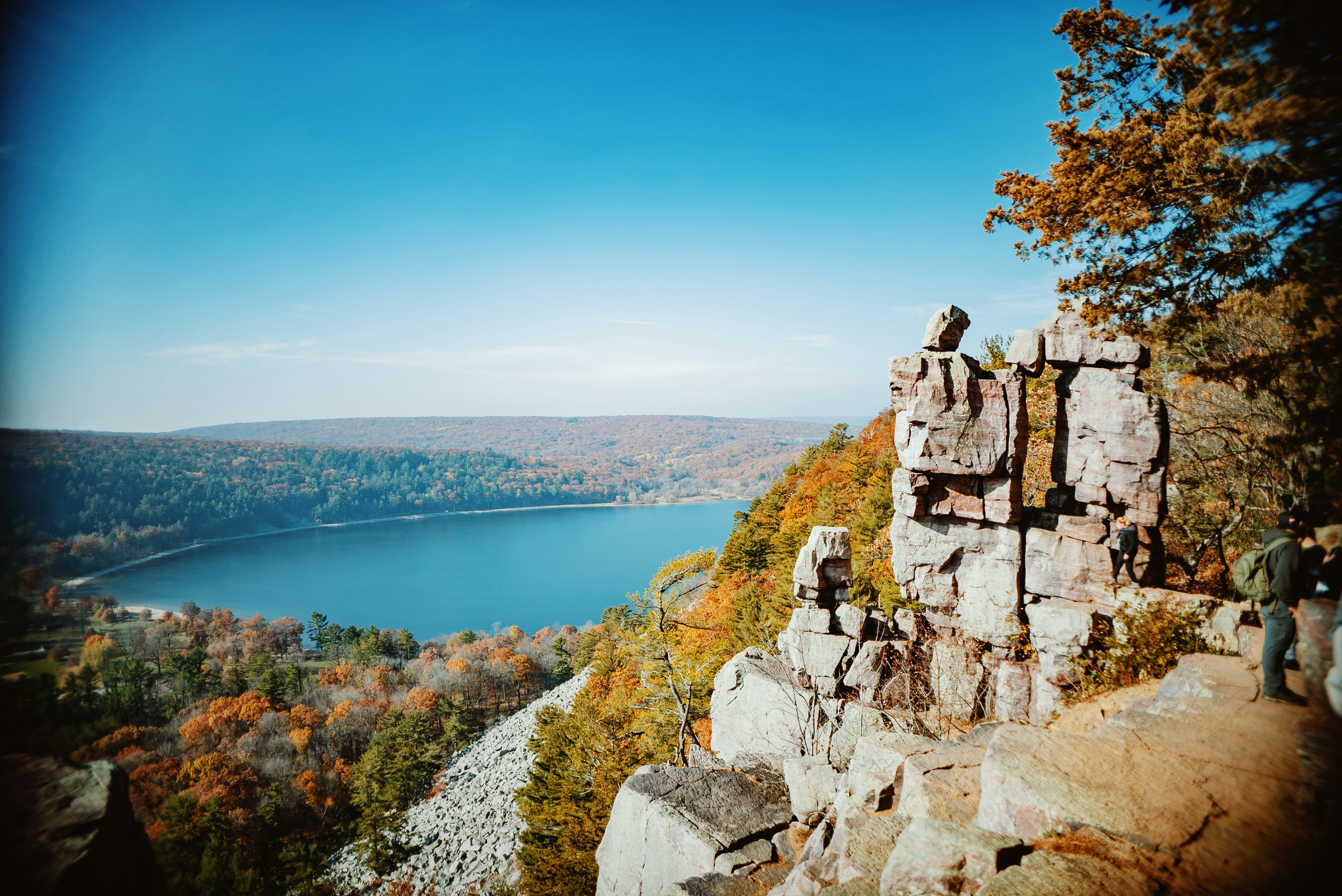 a man standing on top of a cliff next to a lake