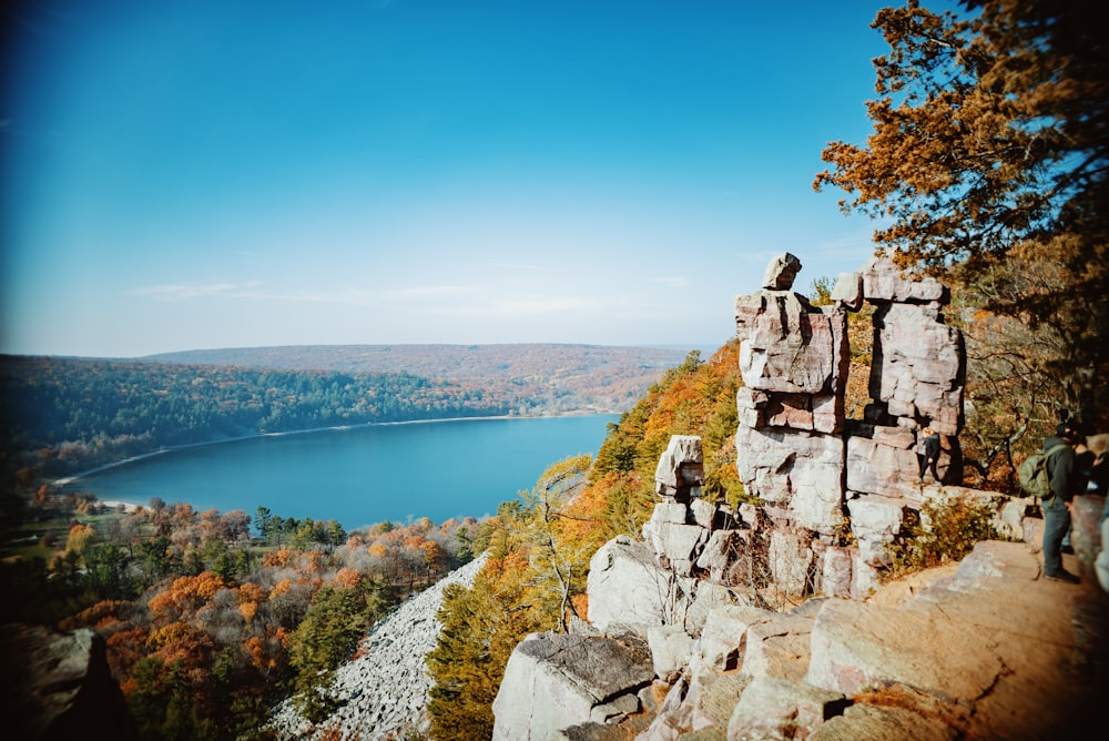 a man standing on top of a cliff next to a lake