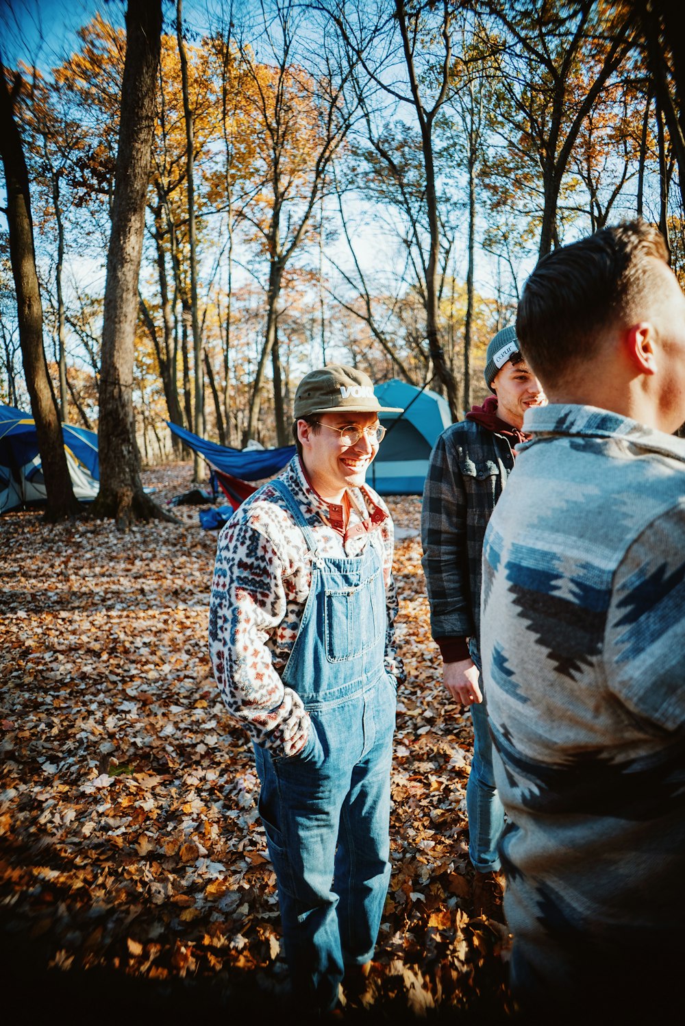 a group of people standing around a tent in the woods