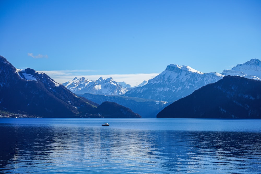 a boat floating on top of a lake surrounded by mountains